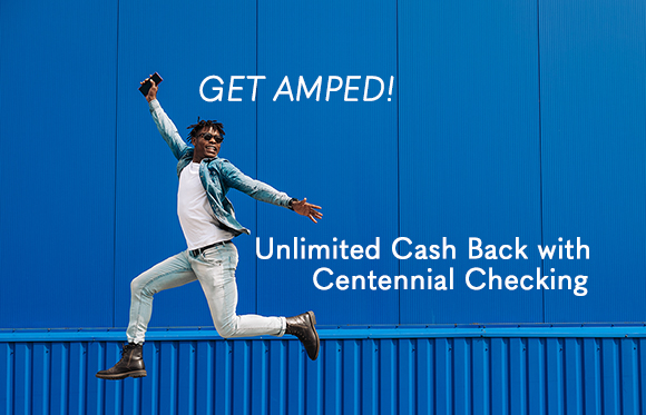 A young man energetically jumps in front of a bright blue container wall, his arms spread wide in excitement. Text overlay reads 'GET AMPED! Unlimited Cash Back with Centennial Checking'.